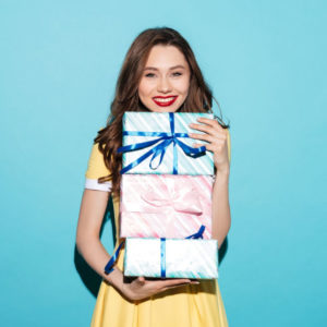 Uśmiechnięta dziewczyna trzyma w rękach prezenty.
